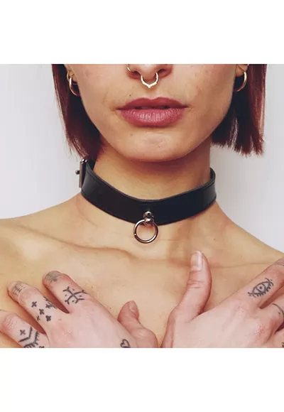 This delicate leather choker is an essential accessory to complete your fetish outfits. This thin leather collar with a silver ring can be worn as a simple piece of jewelry or as a BDSM play accessory.  Its smooth edges prevent injury during restraint play. The ring allows you to attach a leash, rope, etc.  It will adjust perfectly to all neck sizes...